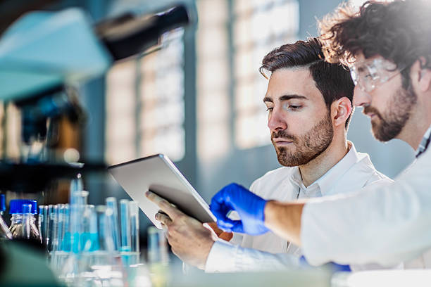 two scientist using digital tablet in laboratory two scientist using digital tablet in laboratory physics stock pictures, royalty-free photos & images