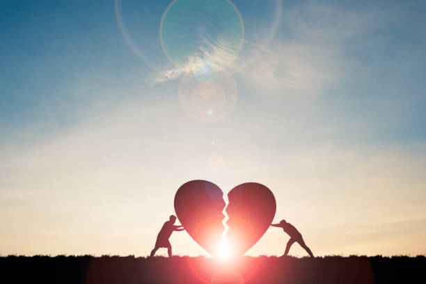 Two silhouette men pushing broken heart with sunlight and blue sky , Valentine 's day concept. Two silhouette men pushing broken heart with sunlight and blue sky , Valentine 's day concept. grief stock pictures, royalty-free photos & images