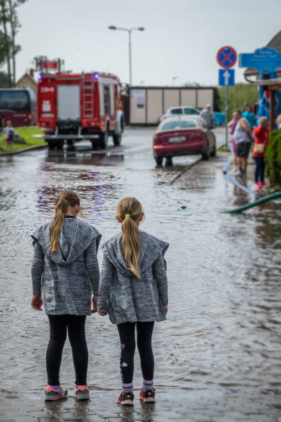 Two sisters looking at an aftermath of torrential rain stock photo