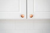 istock Two small round copper door knob on white kitchen cabinet 1397869807
