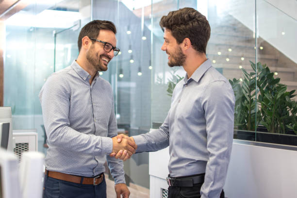 Two smiling business men shaking hands together after successful meeting. stock photo