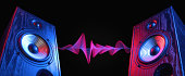 istock Two sound speakers in neon light with sound wave. 1327123770