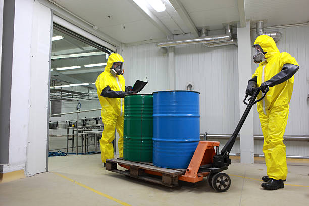 Two specialists dealing with barrels of toxic waste  in factory stock photo