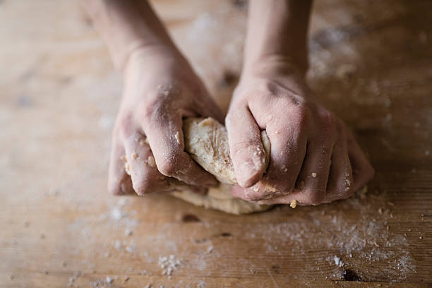 Two strong hands of a baker kneading homemade dough Close-up of two strong hands of a baker that are manually kneading dough on a rough, wooden kitchen table 7 grain bread photos stock pictures, royalty-free photos & images
