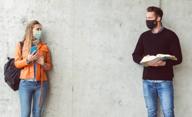 Two students standing in social distance wearing face mask Two students standing in social distance wearing face mask looking at each other distant stock pictures, royalty-free photos & images