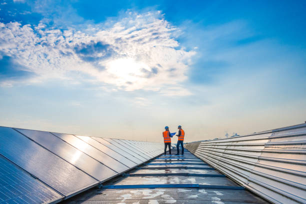 Two technicians in distance discussing between long rows of photovoltaic panels stock photo