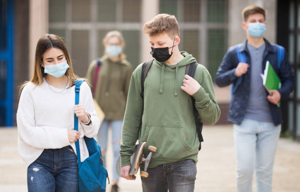 Two teenage students in protective masks stock photo