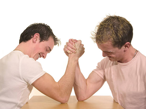 Two teenagers arm wrestling on white background stock photo