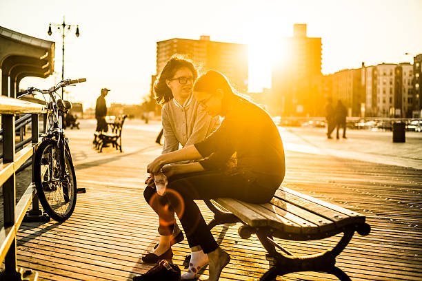 two tennager girls sitting on bench at coney island broadwalk - brighton 個照片及圖片檔