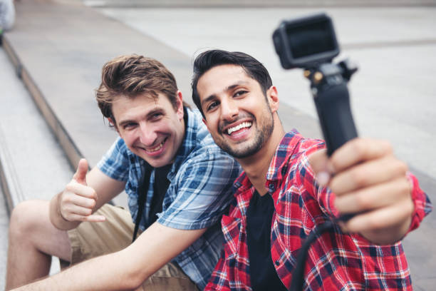 Two traveler or blogger man taking selfie together with action camera sitting on street city stock photo