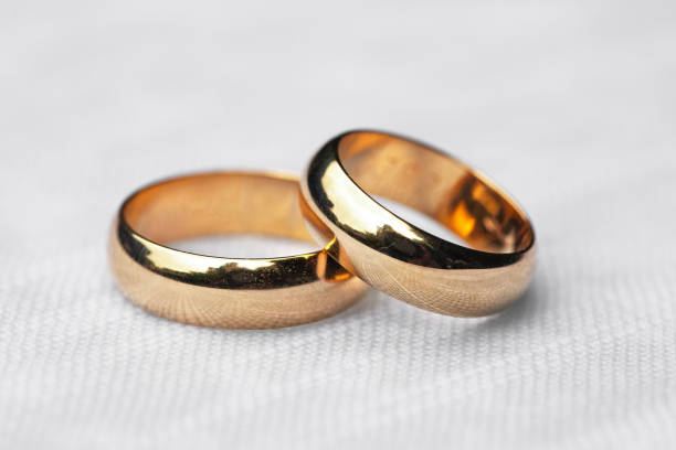 two wedding rings on white tablecloth stock photo