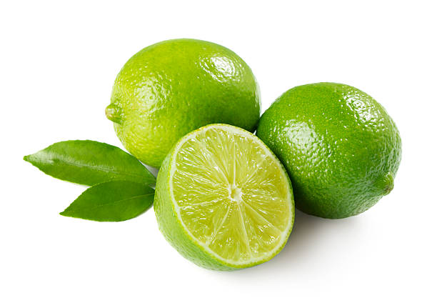 Two whole limes and one halved lime with leaves Two and half ripe limes with leaves isolated on white  lime stock pictures, royalty-free photos & images