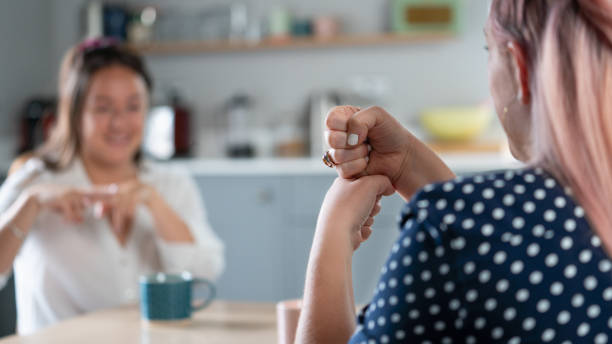 Two Women Having Conversation At Home Using Sign Language Two Women Having Conversation At Home Using Sign Language sign language stock pictures, royalty-free photos & images