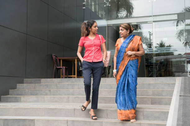 Two women leaving office building, mature woman in sari Young Sri Lankan woman in contemporary clothing talking to older female colleague in traditional dress, they are walking down steps and having conversation sri lanka women stock pictures, royalty-free photos & images