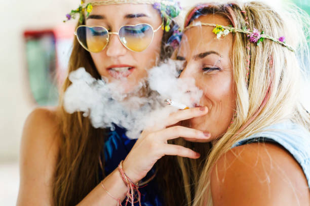 Two women sisters or friends sharing a smoke or joint having fun in summer day - close up real people leisure activity unhealthy living concept  little girl smoking cigarette stock pictures, royalty-free photos & images
