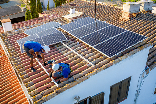 aerial view of two workers installing the guides to place a solar panel in the roof