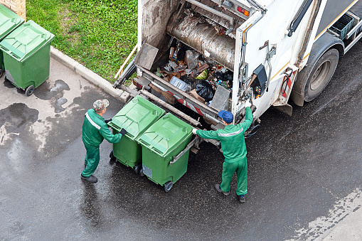 two workers loading mixed domestic waste in waste collection truck - Moscow, 19/08/2020