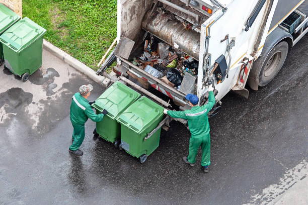 two workers loading mixed domestic waste in waste collection truck stock photo