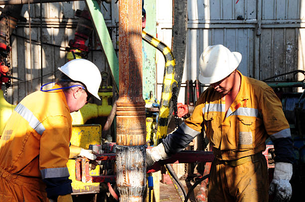 Two workers wearing safety gear using a drill rig stock photo