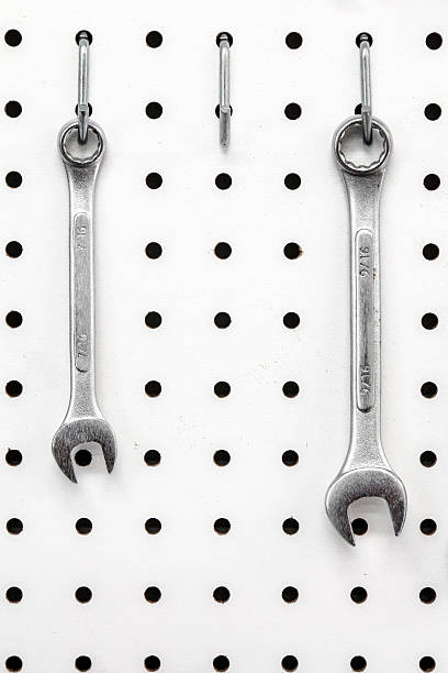 Two wrenches on a white pegboard with an empty slot Image of two wrenches on a white pegboard where three should be.  There is an empty hook of a missing tool in the middle.  The two silver open end wrenches are in the english system.  The pegboard is used to organize tools by hanging them on a wall. pegboard stock pictures, royalty-free photos & images