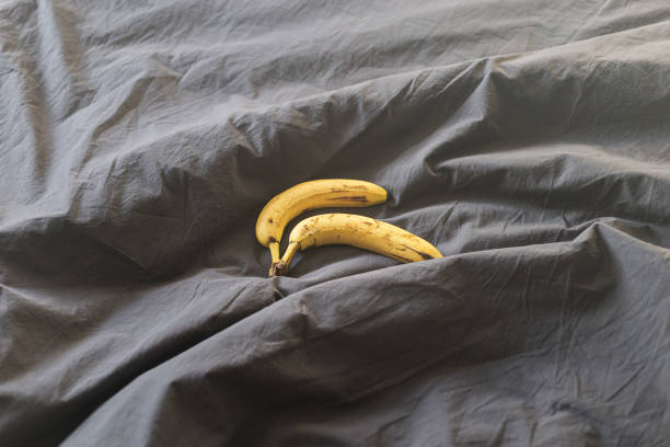 Two yellow bananas are on the bed. Vitamins and a snack before bed  infertile couple stock pictures, royalty-free photos & images