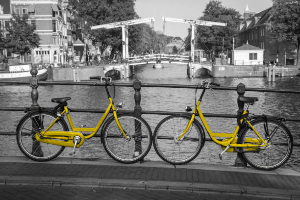 two yellow bikes on the bridge over the channel in amsterdam - zl imagens e fotografias de stock