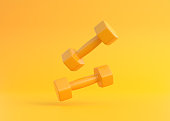 istock Two yellow rubber or plastic coated fitness dumbbells falling on yellow background 1339313606