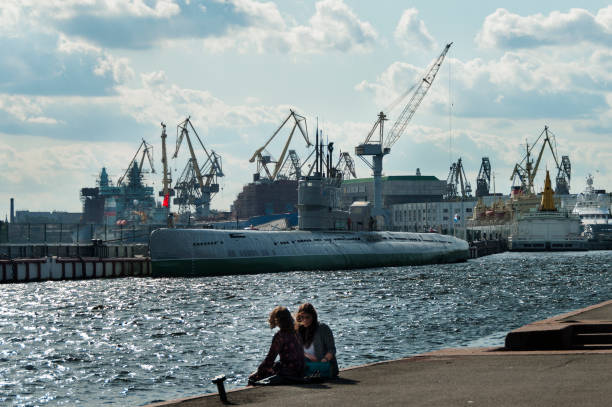 two young girl sit in front of s-189 soviet submarine on Lieutenant Schmidt embankment on right of Neva river SAINT PETERSBURG, RUSSIA - september 12, 2019: two young girl sit in front of museum submarine on Lieutenant Schmidt embankment on right of Neva river girls of saint petersburg stock pictures, royalty-free photos & images