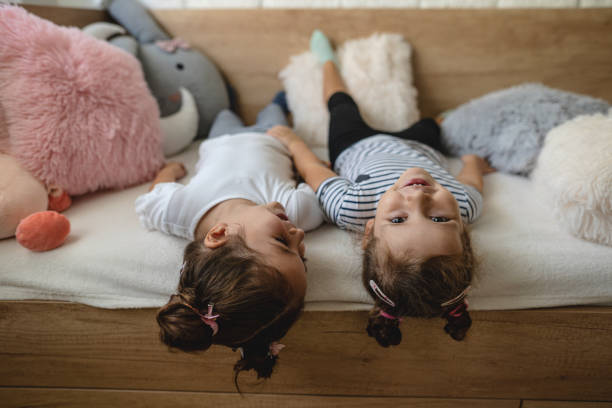 Two young girls laying on the couch upside down stock photo