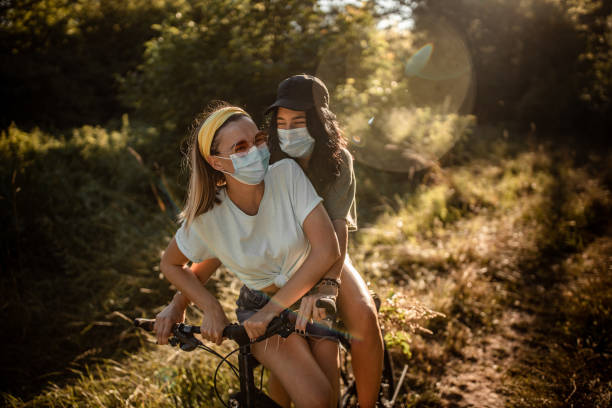 Two young girls with surgical masks having fun in forest stock photo