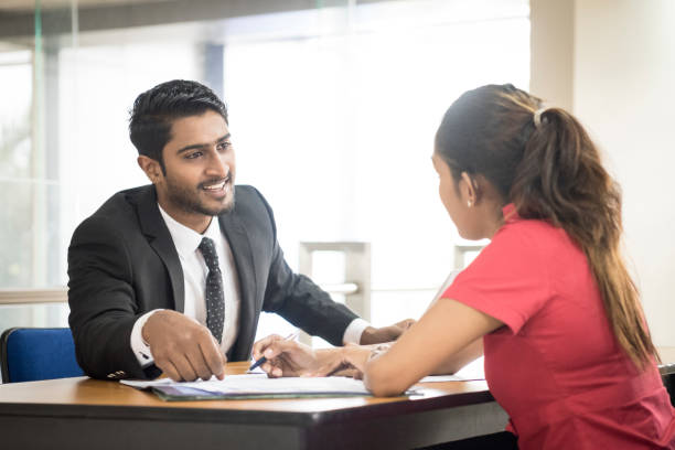 Two young Sri Lankan business colleagues in modern office Young man and woman having meeting at desk in naturally lit interior sri lanka women stock pictures, royalty-free photos & images