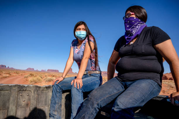 Two young Teenage Navajo Sisters Riding in the bed of a pickup wearing Covid-19 masks to flatten the curve and stop the spread of the Corona Virus Two young Teenage Navajo Sisters Riding in the bed of a pickup wearing Covid-19 masks to flatten the curve and stop the spread of the Corona Virus navajo nation covid stock pictures, royalty-free photos & images