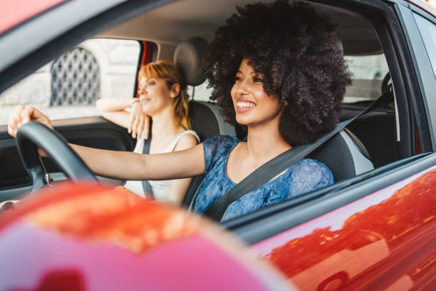 Two young women friends driving in the city - Millennials use the car to get around stock photo