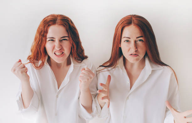 Two young women got angry and shout at the camera! They feel rage, aggression, anger. Two red-haired sisters stand isolated on a white background in spacious oversized shirts Two young women got angry and shout at the camera! They feel rage, aggression, anger. Two red-haired sisters stand isolated on a white background in spacious oversized shirts. vlad model photos stock pictures, royalty-free photos & images