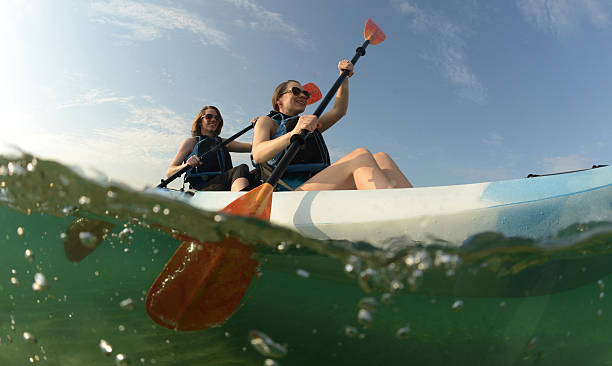 Two young women paddling blue kayak stock photo