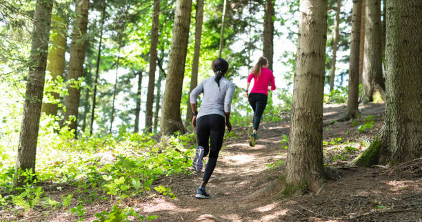 Two Young Women Running In A Forest Two young women running in a forest. cross country running stock pictures, royalty-free photos & images