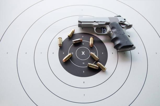 type of .45 bullets on  bullseye target with blurred pistol stock photo