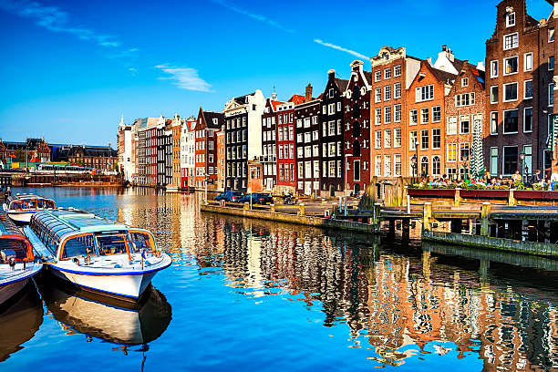 Typical Dutch Houses and Canal in the Center of Amsterdam Typical canal in the center of Amsterdam. Visible are restaurants, sightseeing tourism boats at canal (gracht) waterfront and many typical dutch houses in raw and their reflection in the canal. Amsterdam, Netherlands. canal stock pictures, royalty-free photos & images