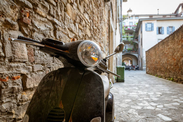 tipica scena di strada in italia con uno scooter nero o un motorino su una vecchia strada stretta acciottorata. concetto di viaggio - bologna napoli foto e immagini stock