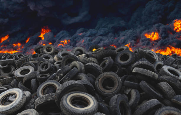Tyres are on fire. Burning old tyres on recycling landfill. Black smoke from tires fire. Tyre graveyard at rubber burning plant. stock photo