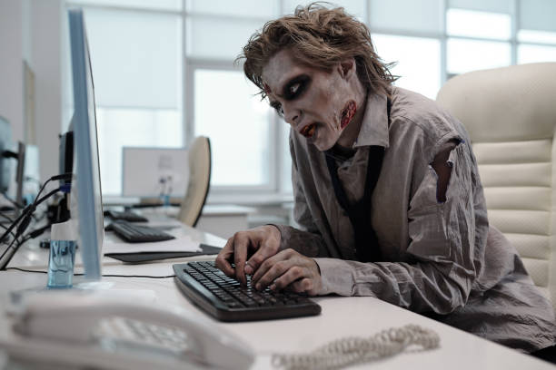 Ugly man with zombie makeup working with computer stock photo