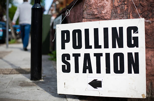 A uk Polling station sign hooked on a wall on a street Directions to a polling station for a UK general election, European election or local election. Shallow depth of field. polling place stock pictures, royalty-free photos & images
