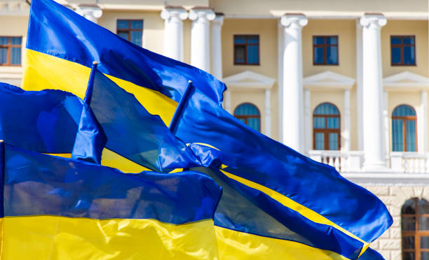 banderas amarillas azules de ucrania evolucionando en un viento cerca de edificio de arquitectura clásica del ayuntamiento con ventanas de arco de columnas y paredes de color rosa y blanco suave, independencia y revolución del concepto de dignidad - ukraine fotografías e imágenes de stock