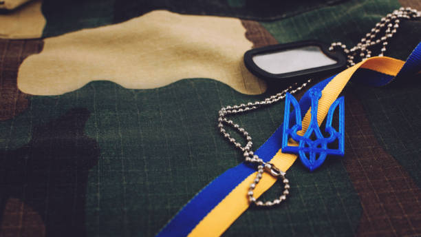 contexte militaire de l'ukraine . symboles nationaux ukrainiens, armoirie, ruban jaune et bleu, jeton sur fond militaire uniforme." n - camouflage ukraine photos et images de collection