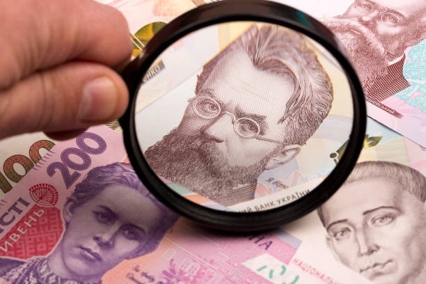 Ukrainian hryvnia in a magnifying glass stock photo