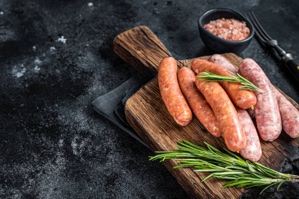 uncooked raw sausages chorizo and bratwurst with spices on wooden board. black background. top view. copy space - chorizo stockfoto's en -beelden
