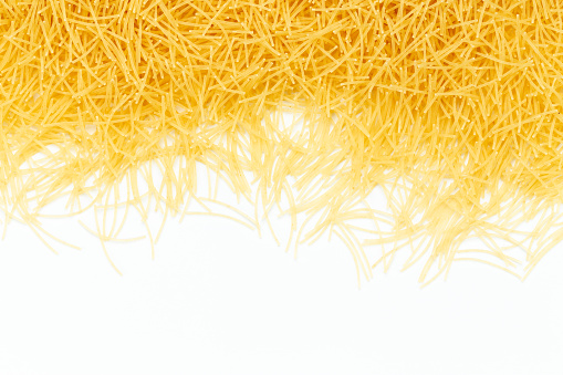 Uncooked vermicelli pasta on white background. Raw dry filini vermicelles. Space for text.