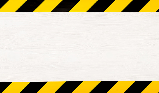 Under construction concept background. Warning tape frame on white wooden surface background with copy space.