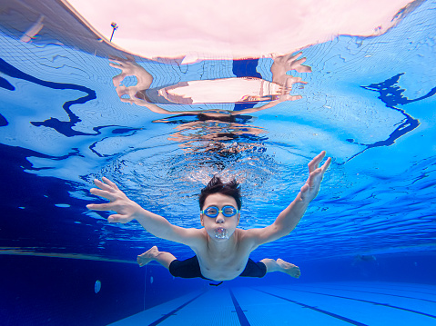 under water view asian chinese teenage boy swimming in swimming pool