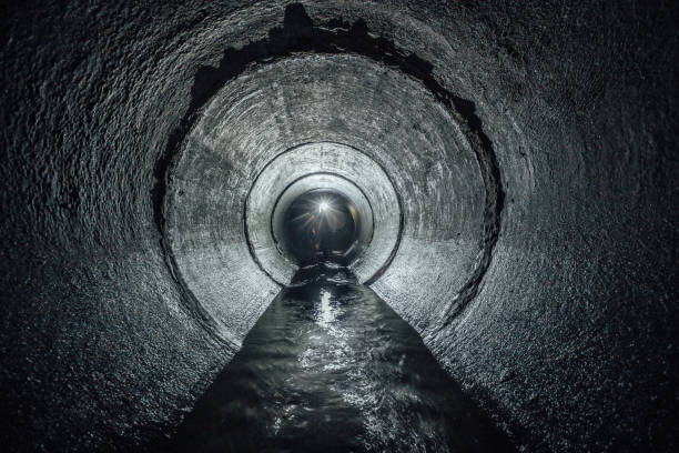unterirdische fluss fließt in runde konkrete kanalisation tunnel. abwasser-sammler - unterirdisch stock-fotos und bilder